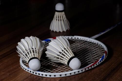 Overhead shot of three white shuttlecocks and a badminton racquet