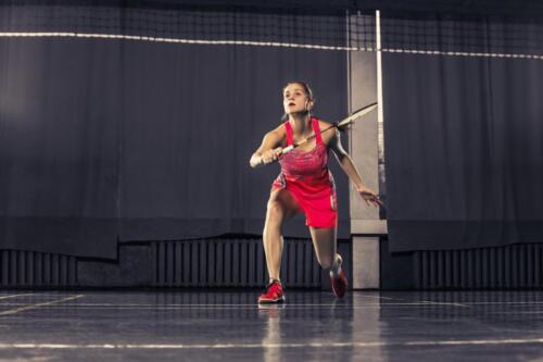 Young woman playing badminton at gym